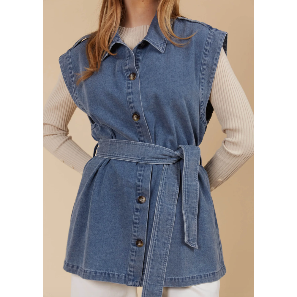 &nbsp;Freya Vest- Denim

Bold yet sophisticated, the Freya Vest redefines seasonal layering with its premium cotton-blend construction and striking design. The full button-down front is complemented by a sharp collar, cap sleeves, and a removable self-fabric belt, offering a tailored silhouette when desired. Whether left open or cinched at the waist, this vest adds a polished finish to any neutral ensemble.